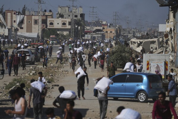 Palestinians carry bags of flour after storming a U.N. World Food Program warehouse in Zawaida, Central Gaza Strip, on Wednesday, May 28, 2025. (AP Photo/Abdel Kareem Hana)