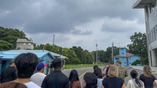 A group of tourists stand near a border station at Panmunjom in the Demilitarized Zone in Paju, South Korea, Tuesday, July 18, 2023. Not long after this photo was taken, Travis King, a U.S. soldier, bolted across the border and became the first known American detained in the North in nearly five years. (AP Photo/Sarah Jane Leslie)