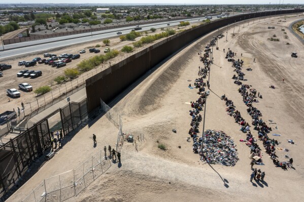 FILE - Migrants form lines outside the border fence waiting for transportation to a U.S. Border Patrol facility in El Paso, Texas, May 10, 2023. Washington's center of gravity on immigration has shifted demonstrably to the right. The debate is now focused on measures meant to keep migrants out as Republicans sense they have the political upper hand. A bipartisan group of senators tasked with finding a border deal this week is running out of time to reach an agreement. (AP Photo/Andres Leighton, File)