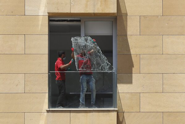 Workers throw a broken window from a damaged apartment a day after an explosion hit the seaport of Beirut, Lebanon, Wednesday, Aug. 5, 2020. Residents of Beirut confronted a scene of utter devastation on Wednesday, a day after a massive explosion at the port rippled across the Lebanese capital, killing at least 100 people, wounding thousands and leaving entire city blocks flooded with glass and rubble. (AP Photo/Hussein Malla)