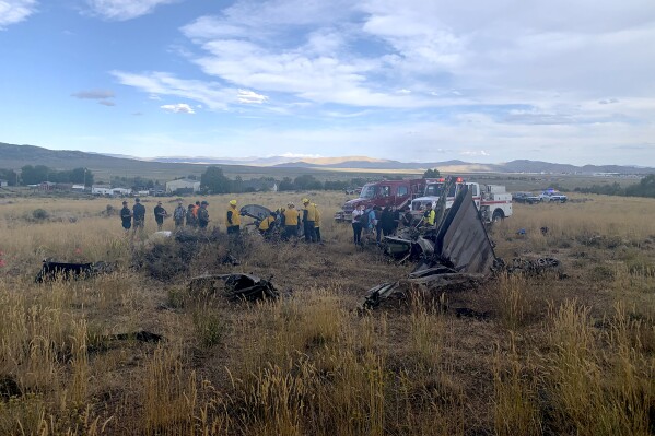 In this photo provided by the Truckee, Calif., Meadows Fire and Rescue Department, members of the Truckee Meadows Fire and Rescue Department and other officials look over aircraft wreckage, Sunday, Sept. 17, 2023, in Reno, Nev., after two California pilots were killed when their planes collided in mid-air while preparing to land after completing a race at the National Championship Air Races north of Reno. (Adam R. Mayberry/Truckee Meadows Fire and Rescue via AP)