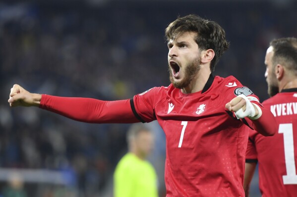 FILE - Georgia's Khvicha Kvaratskhelia, right, celebrates after scoring his side's second goal during the Euro 2024 group A qualifying soccer match between Georgia and Scotland at the Boris Paichadze National Stadium in Tbilisi, Georgia, on Nov. 16, 2023. The country of Georgia is preparing for the biggest soccer match in its history. Having its best player back should help. Napoli forward Khvicha Kvaratskhelia had to sit out Thursday March 21, 2024 Euro 2024 qualifying playoff game against Luxembourg because of a one-game suspension. It didn't matter as his teammate Budu Zivzivadze stepped up to score both goals in a 2-0 win after a crucial red card for Luxembourg. (AP Photo/Tamuna Kulumbegashvili, File)