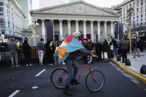 Oscar and his dog Nana arrive on a bike to the Cathedral for a Mass honoring the late Pope Francis, in Buenos Aires, Argentina, Saturday, April 26, 2025. (AP Photo/Natacha Pisarenko)