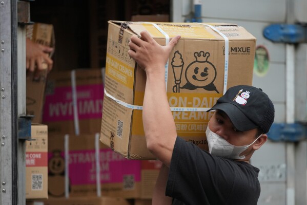 A worker carries a box of supplies for a Mixue store in Jakarta, Indonesia, Wednesday, Feb. 19, 2025. (AP Photo/Achmad Ibrahim)