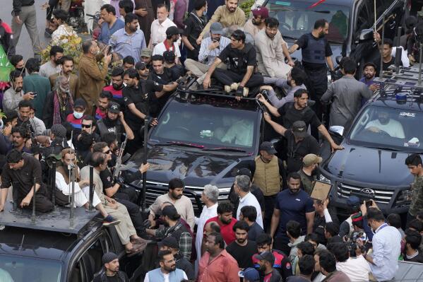 Security personnels and supporters move with a vehicle, center, carrying Pakistan's former Prime Minister Imran Khan during an election campaign rally, in Lahore, Pakistan, Monday, March 13, 2023. Khan rallied thousands of supporters in eastern Pakistan on Monday as courts in the capital, Islamabad, issued two more arrest warrants for him over his failure to appear before judges in graft and terrorism cases, officials said. (AP Photo/K.M. Chaudary)