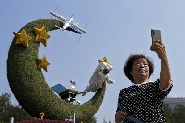A woman takes a souvenir photo with a floral decoration featuring China's space programs celebrating National Day and the 20th party congress in Beijing on Sept. 26, 2022. The U.S. is closely monitoring Chinese activities that potentially threaten American assets in space and is deeply concerned about the rapidly accumulating amount of space debris in low earth orbit, the head of United States military operations in space said Friday, Dec. 9, 2022. (AP Photo/Andy Wong)