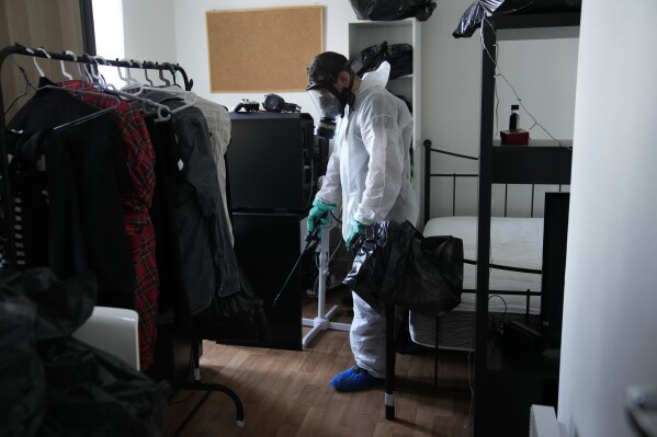 Pest control technician Lucas Pradalier sprays an insecticide under a mattress Wednesday, Oct. 4, 2023 in a Paris apartment floor. The French government has been forced to step in to calm a nation increasingly anxious about bedbugs. (AP Photo/Christophe Ena)