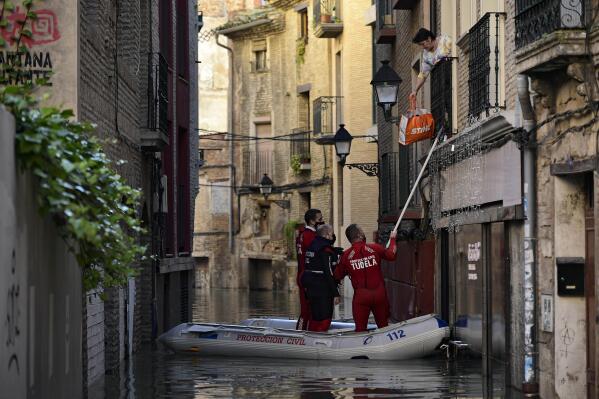 FILE - A rescue team help a woman in her home in a flooded area near the Ebro River in Tudela, northern Spain, Dec. 12, 2021. The United Nations has a new report out Monday, Feb. 28, 2022 on how climate change is harming people and the planet. (AP Photo/Alvaro Barrientos, File)