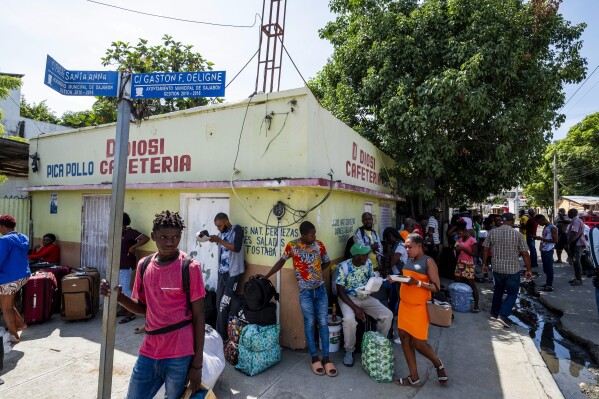 Shoppers stand with bags of merchandise they bought in Dajabón, Dominican Republic, before crossing the border to Haiti, Thursday, Sept. 14, 2023. The president of the Dominican Republic announced Thursday that he would close all borders with neighboring Haiti starting Friday in response to the construction of a supposed canal on Haitian soil that targets waters from the Massacre River, which runs along the border shared by both countries. (AP Photo/Ricardo Hernández)