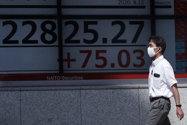 A man walks past an electronic stock board showing Japan's Nikkei 225 index at a securities firm in Tokyo Wednesday, Aug. 12, 2020. Shares were mostly lower in Asia on Wednesday after Wall Street pumped the brakes on its recent rally. (AP Photo/Eugene Hoshiko)