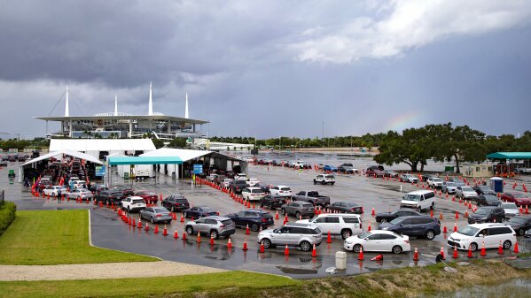 Vehicles line up as healthcare workers help to check-in as citizens are being tested at the COVID-19 drive-thru testing center at Hard Rock Stadium in Miami Gardens on Sunday, Nov. 22, 2020. (David Santiago/Miami Herald via AP)