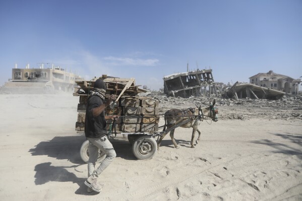Palestinians walk through the destruction left by the Israeli air and ground offensive after they withdrew from Khan Younis, southern Gaza Strip, Sunday, April 7, 2024. (AP Photo/Ismael Abu Dayyah)