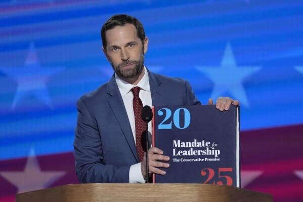 Rep. Jason Crow, D-Colo., holds a copy of Project 2025 as he speaks during the Democratic National Convention, Aug. 22, 2024, in Chicago. (AP Photo/J. Scott Applewhite, File)