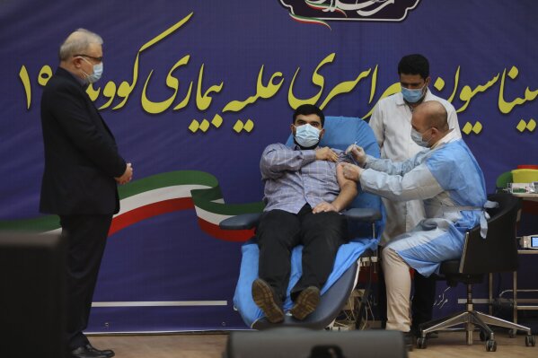 FILE— In this Feb. 9, 2021, file photo, Parsa Namaki, center, son of Health Minister Saeed Namaki, left, is injected with the Russian Sputnik V coronavirus vaccine in a staged event at Imam Khomeini hospital in Tehran, Iran, Iran. Iran has finalized a deal with Russia over purchasing 60 million doses Sputnik V Coronavirus vaccine, state-run IRNA news agency reported Thursday, April 15, 2021. (AP Photo/Vahid Salemi, File)
