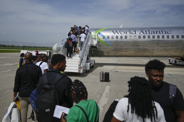 Passengers wait to board a World Atlantic plane at the Toussaint Louverture International Airport in Port-au-Prince, Haiti, Monday, May 20, 2024. Haiti's main international airport reopened Monday for the first time in nearly three months after gang violence forced authorities to close it in early March. (AP Photo/Ramon Espinosa)