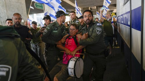 Israeli police officers detain a demonstrator during a protest against plans by Prime Minister Benjamin Netanyahu's government to overhaul the judicial system, at the Ben Gurion Airport in Lod, near Tel Aviv, Israel, Monday, July 3, 2023. (AP Photo/Ohad Zwigenberg)