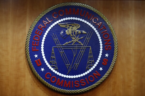 FILE - The seal of the Federal Communications Commission (FCC) is seen before an FCC meeting to vote on net neutrality in Washington, Dec. 14, 2017. The Biden administration and major consumer tech players are launching an effort to put a nationwide cybersecurity certification and labeling program in place to help consumers choose smart devices that are less vulnerable to hacking. Officials liken the new 