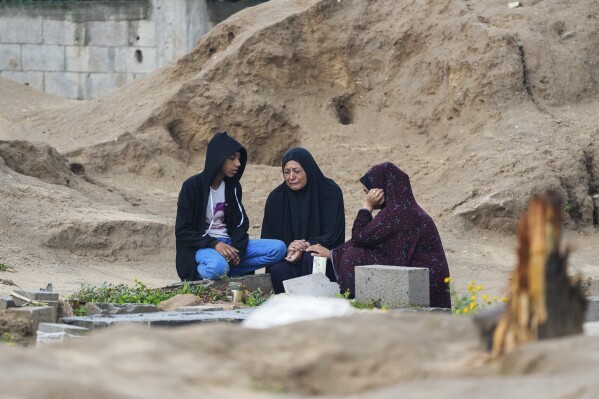 Palestinians visit the graves of their relatives who were killed in the war between Israel and the Hamas militant group on the first day of the Muslim holiday of Eid al-Fitr, in Deir al-Balah, Gaza, Wednesday, April 10, 2024. (AP Photo/Abdel Kareem Hana)