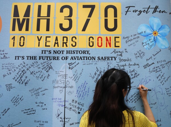 A woman writes well messages on a message board during the tenth annual remembrance event at a shopping mall, in Subang Jaya, on the outskirts of Kuala Lumpur, Malaysia, Sunday, March 3, 2024. Ten years ago, a Malaysia Airlines Flight 370, had disappeared March 8, 2014 while en route from Kuala Lumpur to Beijing with over 200 people on board. (AP Photo/FL Wong)