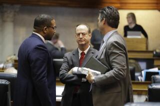 FILE - State Sen. Mark Messmer, center, R-Jasper, talks with Sen. Eddie Melton, left, D-Gary, and Sen. Ryan Mishler, R-Bremen, following a session at the Statehouse, Tuesday, April 23, 2019, in Indianapolis. An Indiana Senate panel on Wednesday, Feb. 16, 2022, endorsed rolling back a proposal that aimed to severely limit workplace COVID-19 vaccine requirements, setting up weeks of negotiations with House members on how far the Republican-dominated Legislature will go toward inserting itself on the issue. (AP Photo/Darron Cummings File)
