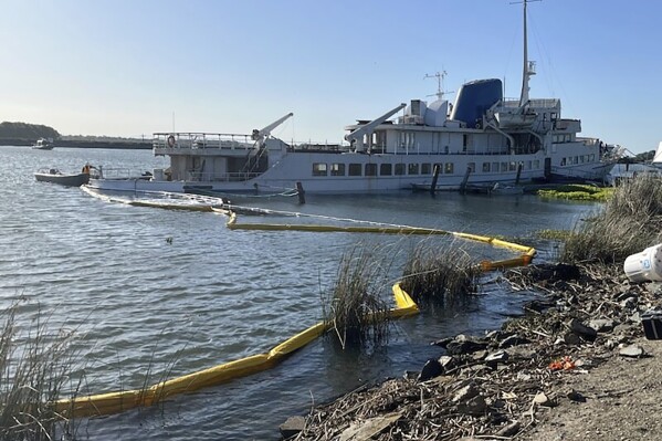 This photo provided by the U.S. Coast Guard District 11 shows The Aurora, a non-operational 294-foot cruise ship moored northwest of Stockton, Wednesday, May 22, 2024, that began to sink and discharge product. A containment boom has been placed around the defunct 1950s-era cruise ship that began sinking and leaking pollution in California's Sacramento-San Joaquin River Delta, authorities said. (California Department of Fish and Wildlife via AP)