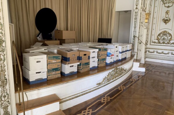 FILE - This image, contained in the indictment against former President Donald Trump, and partially redacted by source, shows boxes of records being stored on the stage in the White and Gold Ballroom at Trump's Mar-a-Lago estate in Palm Beach, Fla. The federal judge overseeing the classified documents prosecution of Trump is expected to set a trial date during a court hearing on March 1, 2024.(Justice Department via AP)