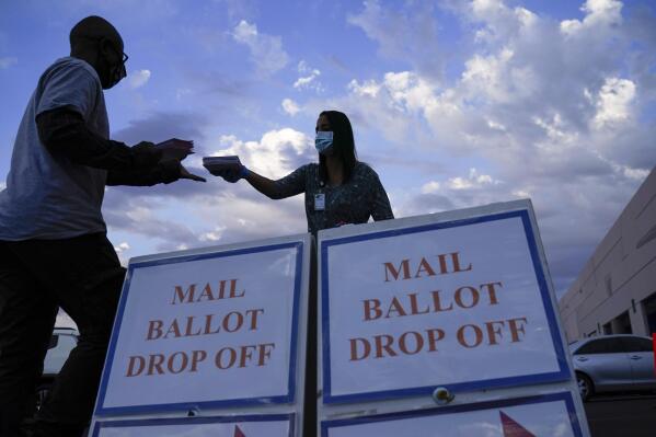 FILE - A county worker collects a mail-in ballots in a drive-thru mail-in ballot drop off area at the Clark County Election Department in Las Vegas, Nov. 2, 2020. In most states, you can drop off a ballot for someone else — but there might be restrictions.  For example, some states only allow caregivers, family members or household members to drop off your ballot for you. Other states allow you to give your ballot to anyone you choose. More than half of states have laws that explicitly allow a third party to return a voted ballot. Laws allowing ballot collection make voting more convenient, but they have been criticized by some who say they increase risk of voter fraud. (AP Photo/John Locher, File)