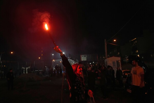 An Iranian woman holds up a firework celebrating Chaharshanbe Souri, or Wednesday Feast, an ancient Festival of Fire on the eve of the last Wednesday of the Persian year, in Tehran, Iran, Tuesday, March 18, 2025. (AP Photo/Vahid Salemi)