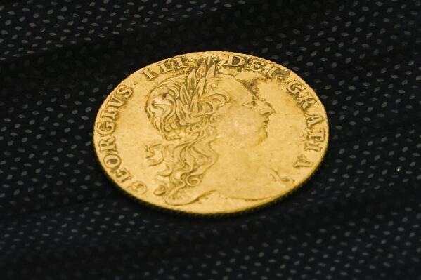 Shown is a King George III gold guinea, discovered in an excavation site at the Red Bank Battlefield Park in National Park, N.J., Tuesday, Aug. 2, 2022. Researchers believe they have uncovered in a mass grave in New Jersey the remains of as many as 12 Hessian soldiers who fought during the Revolutionary War, officials announced Tuesday. (AP Photo/Matt Rourke)