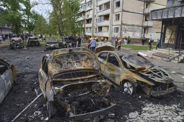 Municipal workers clean up burnt cars in the residential area following Russia's drone attack in Kyiv, Ukraine, Sunday, May 4, 2025. (AP Photo/Efrem Lukatsky)