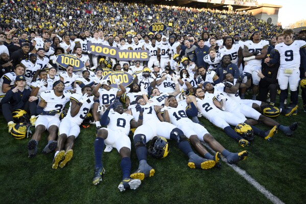 Michigan poses for photographers after an NCAA college football game that earned them their 1,000 win in school history, Saturday, Nov. 18, 2023, in College Park, Md. Michigan won 31-24. (AP Photo/Nick Wass)