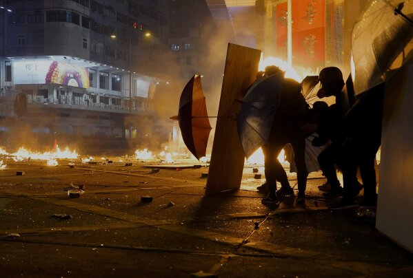 Protestors react as police fire tear gas in the Kowloon area of Hong Kong, Monday, Nov. 18, 2019. As night fell in Hong Kong, police tightened a siege Monday at a university campus as hundreds of anti-government protesters trapped inside sought to escape. (AP Photo/Vincent Yu)
