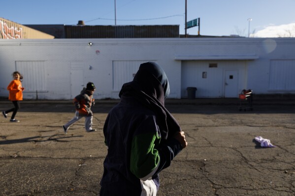 Juan, a 7-year-old from San Juan del Rio, Mexico, picks up a piece of clothing from a pile of clothes outside a migrant shelter near the 2300 block of South Halsted Street of Chicago on Monday, Dec. 18, 2023. Five-year-old Jean Carlos Martinez Rivero, who was staying at the shelter, died Sunday. (Armando L. Sanchez/Chicago Tribune via AP)