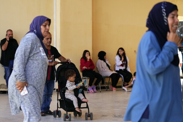 Residents displaced from south Lebanon, walk at a school being used as a shelter in the southern port city of Tyre, Lebanon, Friday, Oct. 20, 2023. More than 4,200 people have been displaced from villages in south Lebanon by clashes on the border with Israel, and local officials said Friday that they are ill-prepared for the much larger exodus that would ensue if the limited conflict escalates to an all-out war. (AP Photo/Hassan Ammar)