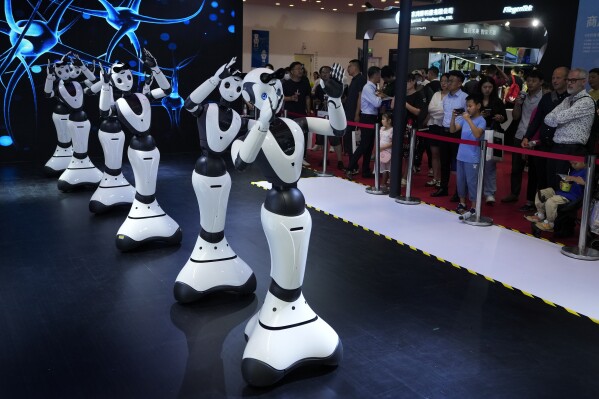 Visitors look at robots perform on stage during the annual World Robot Conference at the Etrong International Exhibition and Convention Center on the outskirts of Beijing, Thursday, Aug. 17, 2023. (AP Photo/Andy Wong)
