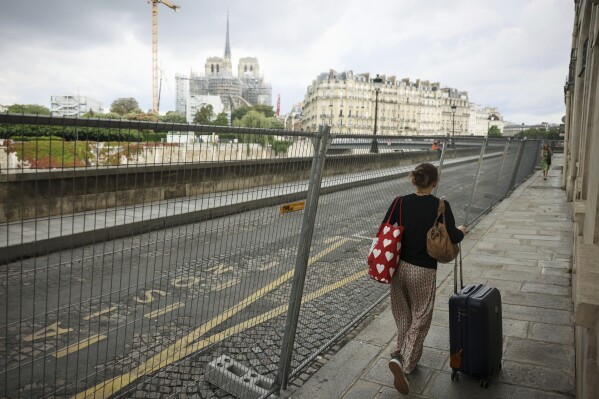 FILE - A woman pulls her luggage along fences of the security perimeter, with Notre Dame cathedral in background, at the 2024 Summer Olympics, Sunday, July 21, 2024, in Paris, France. French prosecutors are investigating an alleged rape of an Australian woman visiting Paris, just two days before the start of the 2024 Olympics. A 25-year-old Australian woman has reported to Paris authorities that she was gang raped last week, a statement from the public prosecutor’s office in the French capital said on Wednesday, July 24, 2024. (ĢӰԺ Photo/Thomas Padilla, File)