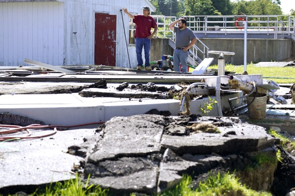 Joe Gaudiana, the Ludlow, Vt. chief water and sewer operator, left, surveys damage with Elijah Lemieux, of the Vermont Rural Water Association, at the wastewater treatment plant following July flooding, Wednesday, Aug. 2, 2023, in Ludlow. Across the U.S., municipal water systems and sewage treatment plants are at increasing risk of damage from floods and sea-level rise brought on in part or even wholly by climate change. The storm that walloped Ludlow especially hard, damaging the picturesque ski town’s system for cleaning up sewage before it’s discharged into the Williams River. (AP Photo/Charles Krupa)