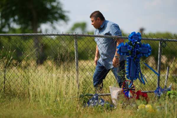Adriane Reyes adds a cross to candles, flowers and notes to create a Makeshift Memorial for voice actor Jonathan Joss who was recently killed in San Antonio on Tuesday, June 3, 2025. (AP Photo/Eric Gay)