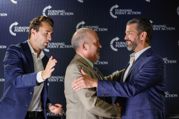 Former Wisconsin Attorney General and state Supreme Court candidate Brad Schimel, middle, greets Donald Trump Jr., as Charlie Kirk looks on during a town hall Monday, March 17, 2025, in Oconomowoc, Wis. (AP Photo/Jeffrey Phelps)
