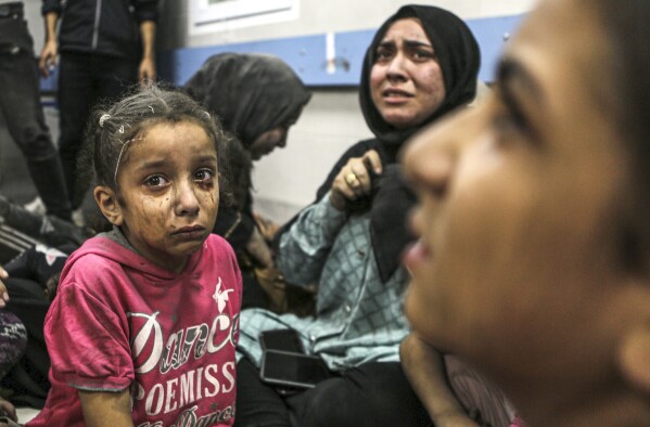 Wounded Palestinians sit in al-Shifa hospital in Gaza City, central Gaza Strip, after arriving from al-Ahli hospital following an explosion there, Tuesday, Oct. 17, 2023. The Hamas-run Health Ministry says an Israeli airstrike caused the explosion that killed hundreds at al-Ahli, but the Israeli military says it was a misfired Palestinian rocket. (AP Photo/Abed Khaled)