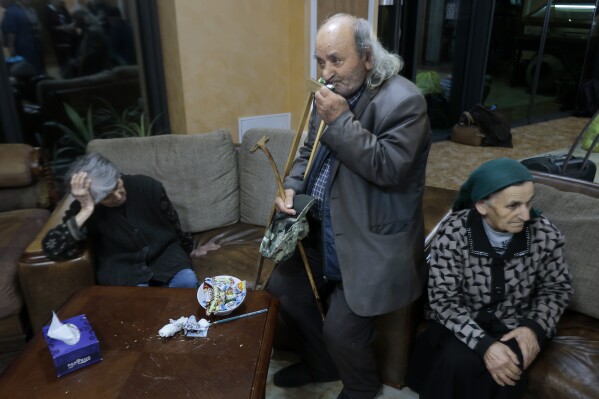 An ethnic Armenian fleeing Nagorno-Karabakh helps himself to a treat as he waits to be temporarily checked into a hotel in Goris, in Armenia's Syunik region, Sunday, Sept. 24, 2023. (AP Photo/Vasily Krestyaninov)