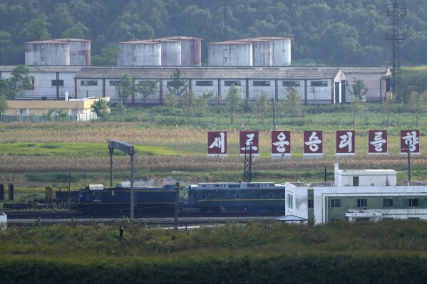 A green train with yellow trimmings, resembling one used by North Korean leader Kim Jong Un on his previous travels, is seen steaming by a slogan which reads 