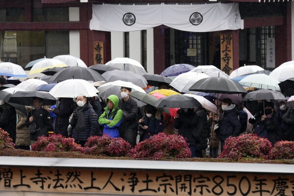 People are waiting in the rain to attend the 