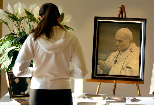 ARCHIVO - Anna Buss, feligresa de Santa María Goretti, de 10 años, hace una pausa frente a un santuario dedicado al Papa Juan Pablo II antes de la misa del sábado 2 de abril de 2005, en Madison, Wisconsin (John Maniaci/Wisconsin State Journal vía AP, Archivo)