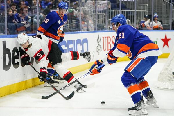 Ottawa Senators' Nick Holden (5) vies for control of the puck with New York Islanders' Josh Bailey (12) and Kyle Palmieri (21) during the second period of an NHL hockey game Tuesday, March 22, 2022, in Elmont, N.Y. (AP Photo/Frank Franklin II)