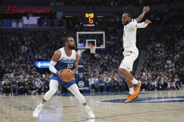 Minnesota Timberwolves guard Mike Conley (10) looks to shoot as Cleveland Cavaliers guard Darius Garland defends during the first half of an NBA basketball game Friday, March 22, 2024, in Minneapolis. (AP Photo/Abbie Parr)