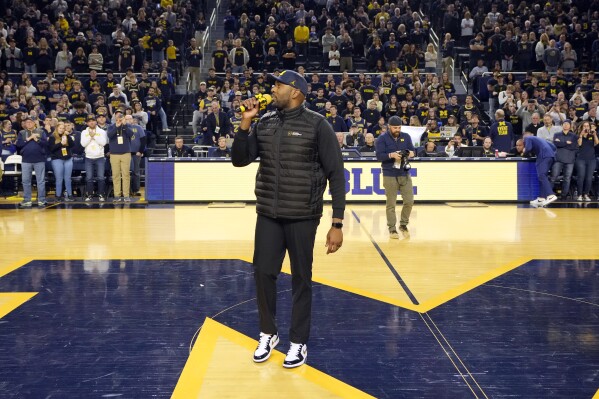 Michigan football coach Sherrone Moore addresses the crowd during the first half of an NCAA college basketball game between Michigan and Iowa, Saturday, Jan. 27, 2024, in Ann Arbor, Mich. Moore, who had been offensive coordinator, was hired to replace Jim Harbaugh, who left for the Los Angeles Chargers. (AP Photo/Carlos Osorio)