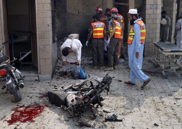 Pakistani security officials and rescue workers gather at the site of a bombing on an entrance of a hospital in Dera Ismail Khan, Pakistan, Sunday, July 21, 2019. Police in Pakistan say gunmen opened fire on a police post and then bombed the entrance to a hospital as the wounded were being brought in.(AP Photo/Ishtiaq Mahsud)