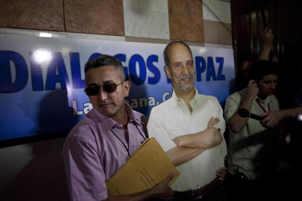A peace talk delegation member with the Revolutionary Armed Forces of Colombia, or FARC, left, carries a lifesize image of imprisoned rebel Commander Jaime Palmera, alias "Simon Trinidad," who is serving time in the U.S. federal penitentiary in Florence, Colorado, at the start of talks in Havana, Cuba, Monday, Nov. 19, 2012. Cuba is playing host to the talks in Havana following an initial round of discussions in Oslo, Norway. The FARC has been at war with the Colombian government for nearly half a century. (AP Photo/Ramon Espinosa)