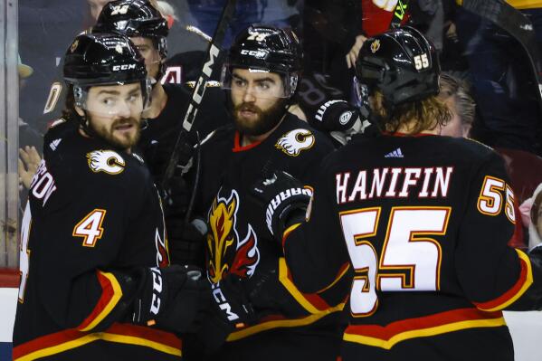Calgary Flames forward Dillon Dube, center, celebrates his goal with teammates Rasmus Andersson, left, and Noah Hanifin during the third period of an NHL hockey game against the Tampa Bay Lightning in Calgary, Alberta, Saturday, Jan. 21, 2023. (Jeff McIntosh/The Canadian Press via AP)